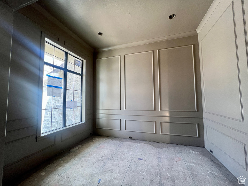 Empty room with plenty of natural light, a decorative wall, and ornamental molding