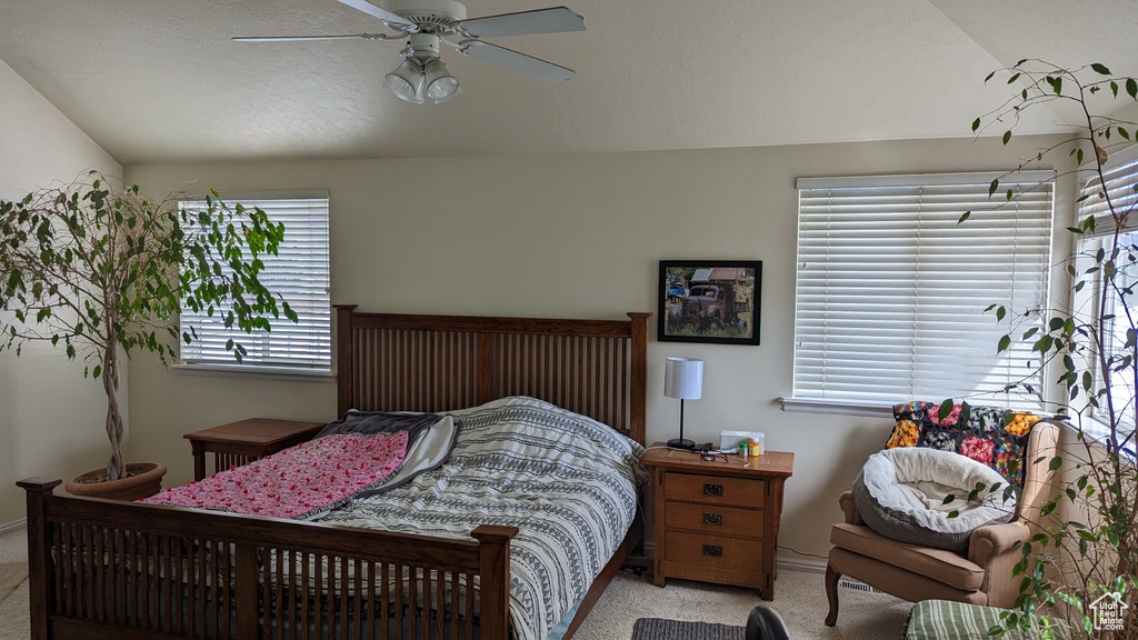 Bedroom with light colored carpet, vaulted ceiling, a ceiling fan, and baseboards