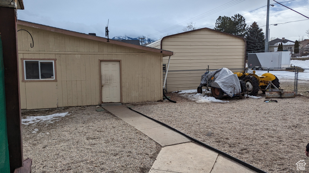 View of outdoor structure with fence and an outbuilding