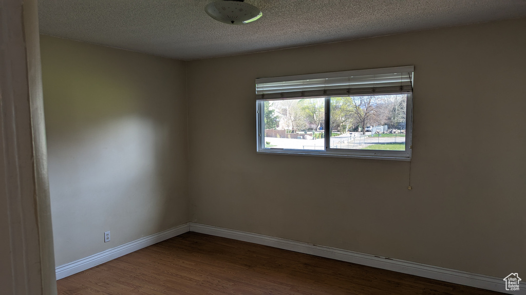 Empty room featuring wood finished floors, baseboards, and a textured ceiling