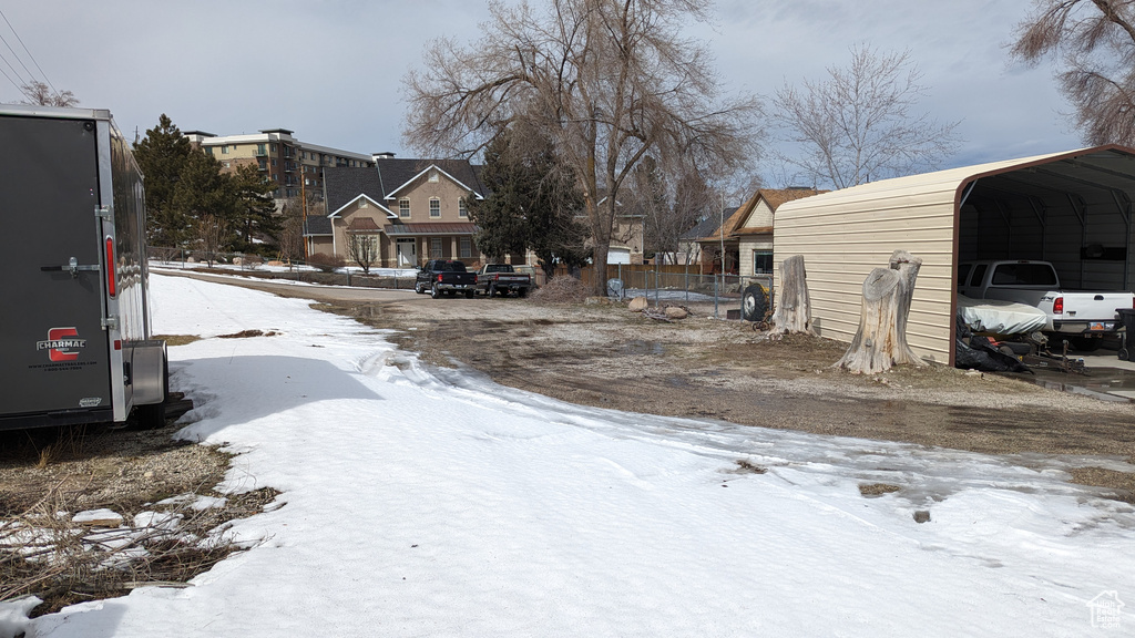 Snowy yard featuring a carport and a residential view