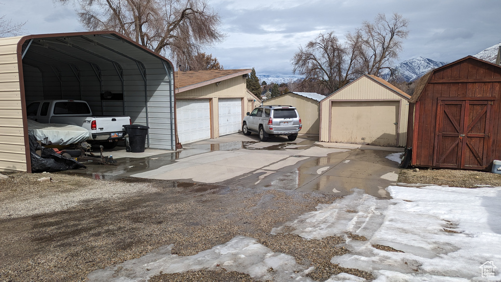 Snow covered garage with a carport and a detached garage
