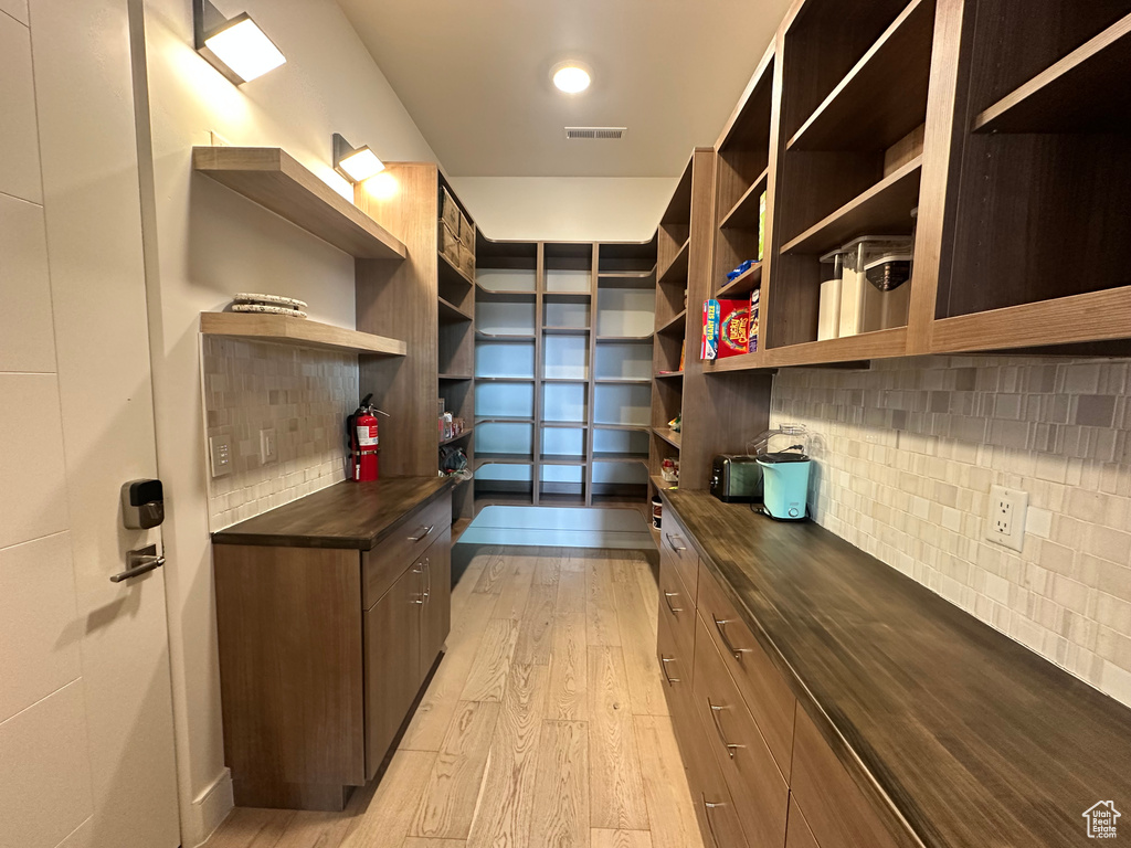 Walk in closet with light wood-type flooring