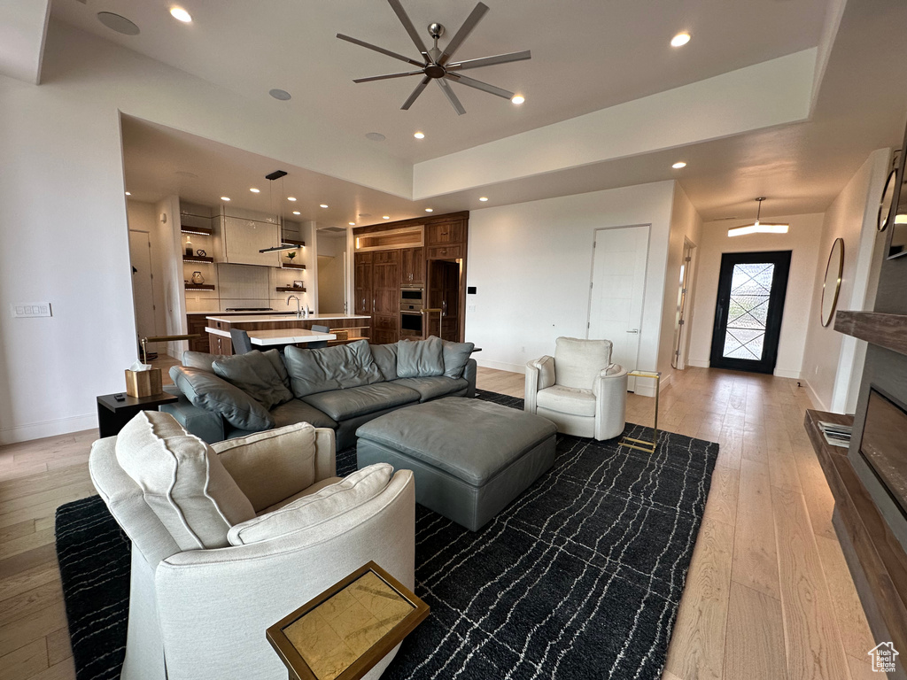 Living room with light wood-style floors, baseboards, a ceiling fan, and recessed lighting