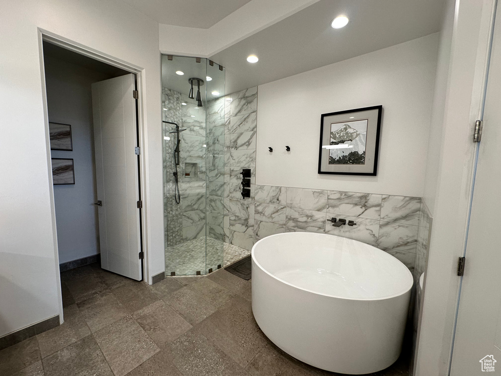 Bathroom featuring recessed lighting, a marble finish shower, a freestanding bath, tile walls, and baseboards