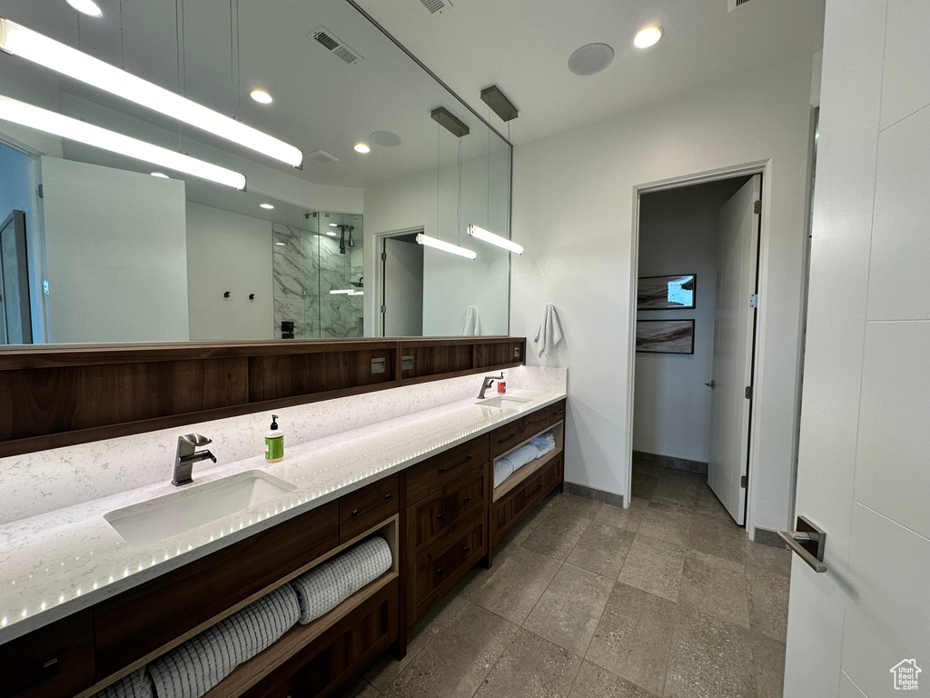 Full bath featuring a shower stall, baseboards, double vanity, and recessed lighting