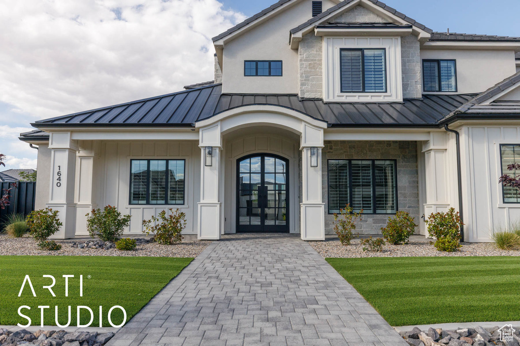 Property entrance with a standing seam roof, a yard, and board and batten siding