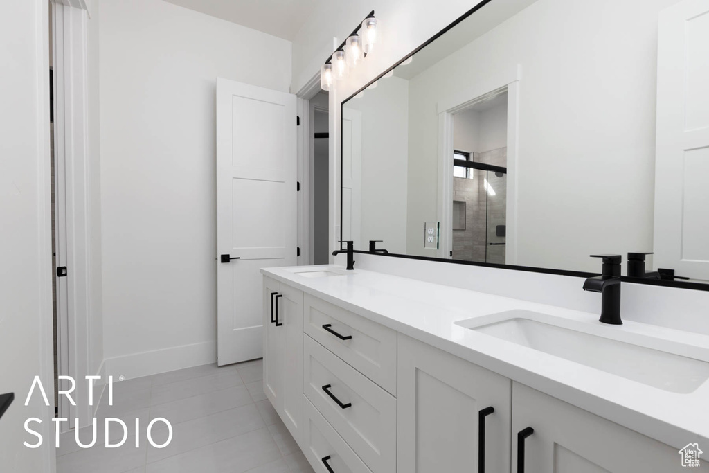 Bathroom with a stall shower, double vanity, tile patterned flooring, and baseboards