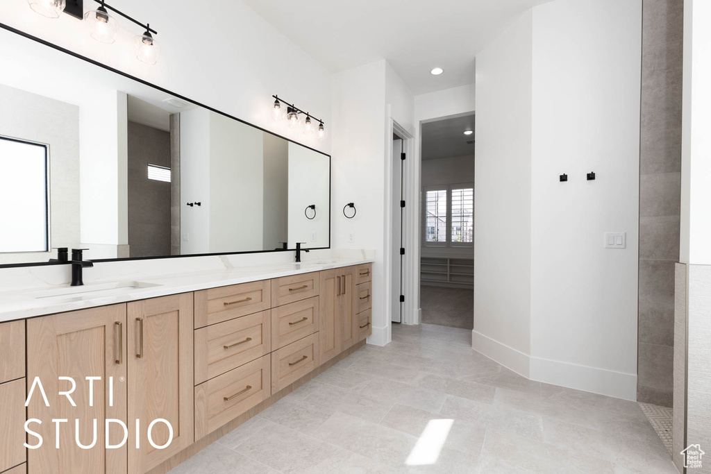 Bathroom featuring double vanity, baseboards, and recessed lighting