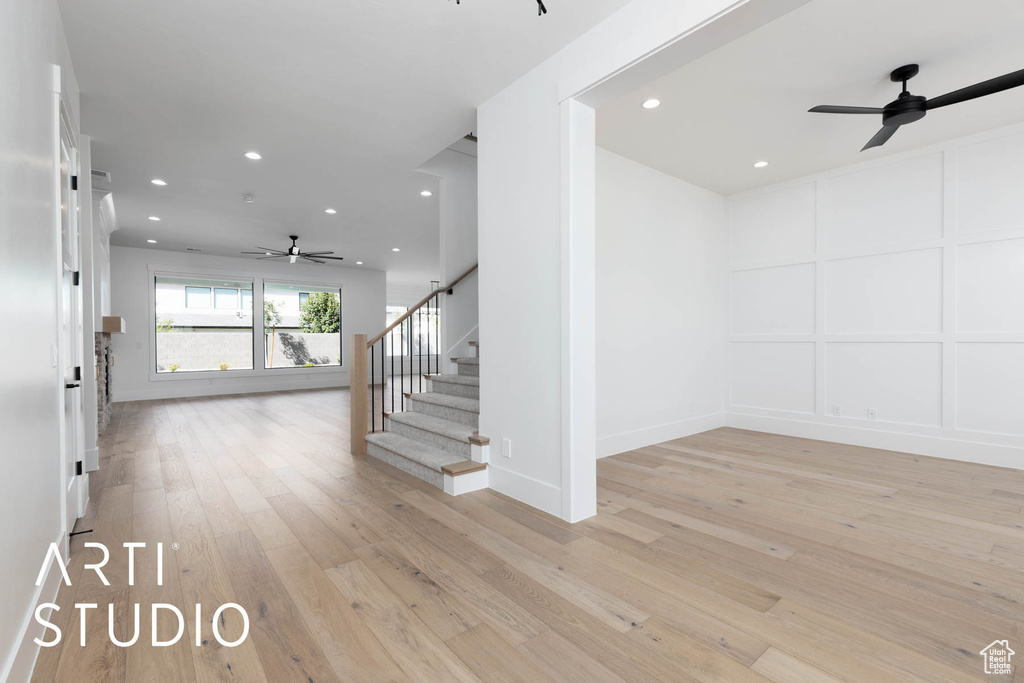 Staircase with ceiling fan, recessed lighting, wood finished floors, baseboards, and a decorative wall