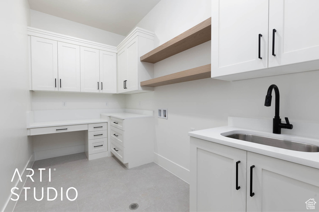 Clothes washing area with baseboards, washer hookup, and cabinet space