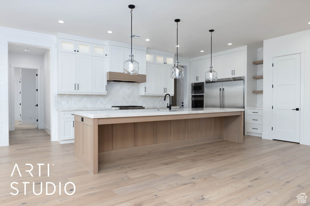 Kitchen featuring built in appliances, light countertops, white cabinetry, decorative backsplash, and recessed lighting