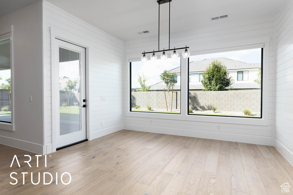 Unfurnished dining area with wood finished floors, wood walls, and baseboards