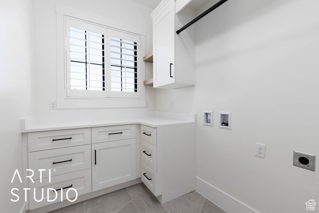 Laundry area with electric dryer hookup, cabinet space, hookup for a washing machine, light tile patterned flooring, and baseboards