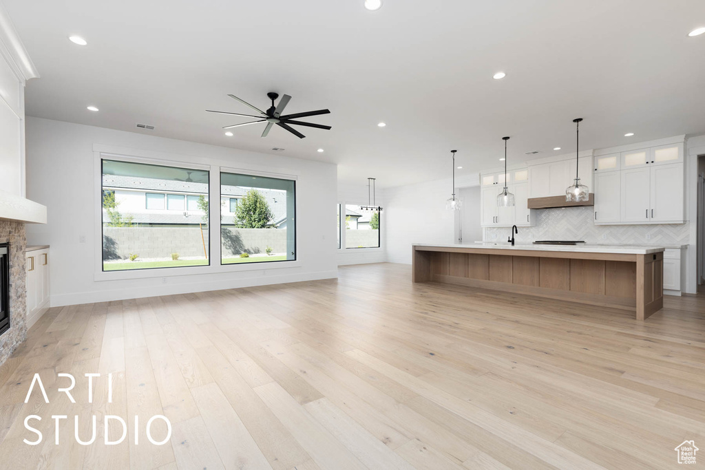Unfurnished living room with a ceiling fan, a fireplace, light wood finished floors, recessed lighting, and baseboards
