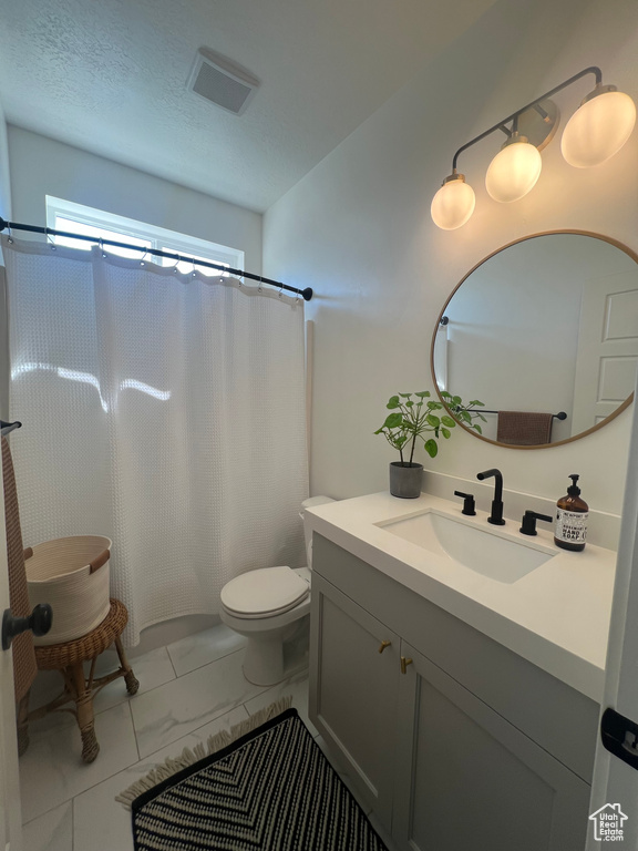Bathroom featuring vanity, toilet, marble finish flooring, and a shower with shower curtain