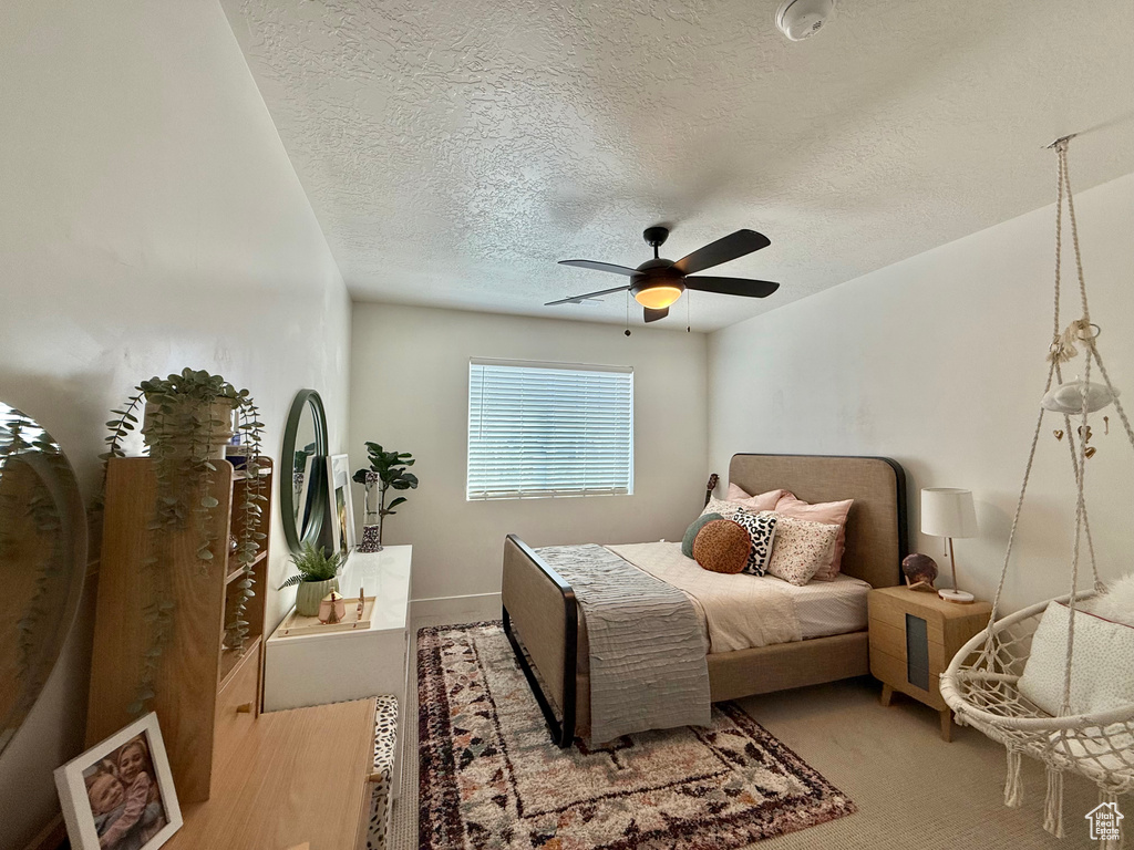 Bedroom featuring a textured ceiling, ceiling fan, and light colored carpet