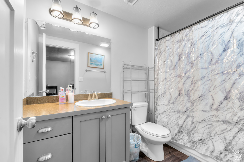Full bath featuring wood finished floors, vanity, toilet, and a shower with curtain