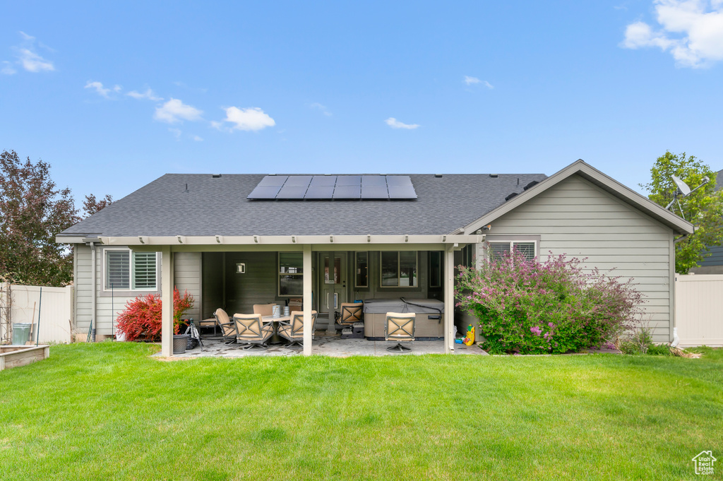 Rear view of house with a patio, a hot tub, solar panels, and roof with shingles