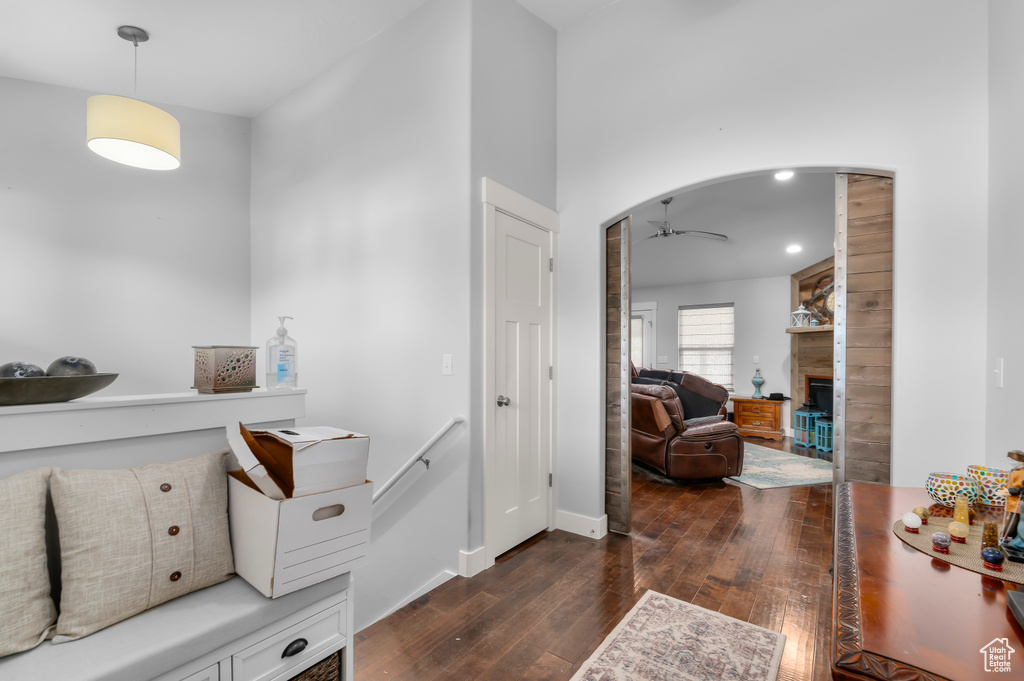 Foyer entrance with dark wood-style floors, ceiling fan, a fireplace, arched walkways, and baseboards