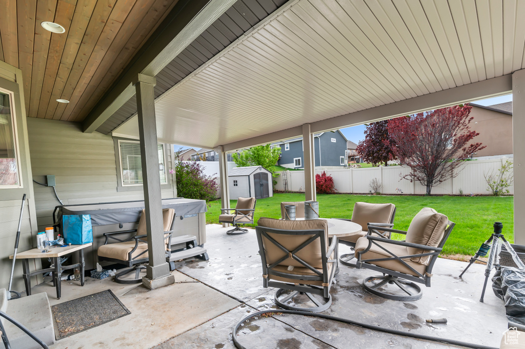 View of patio featuring a storage shed, a hot tub, and an outdoor structure