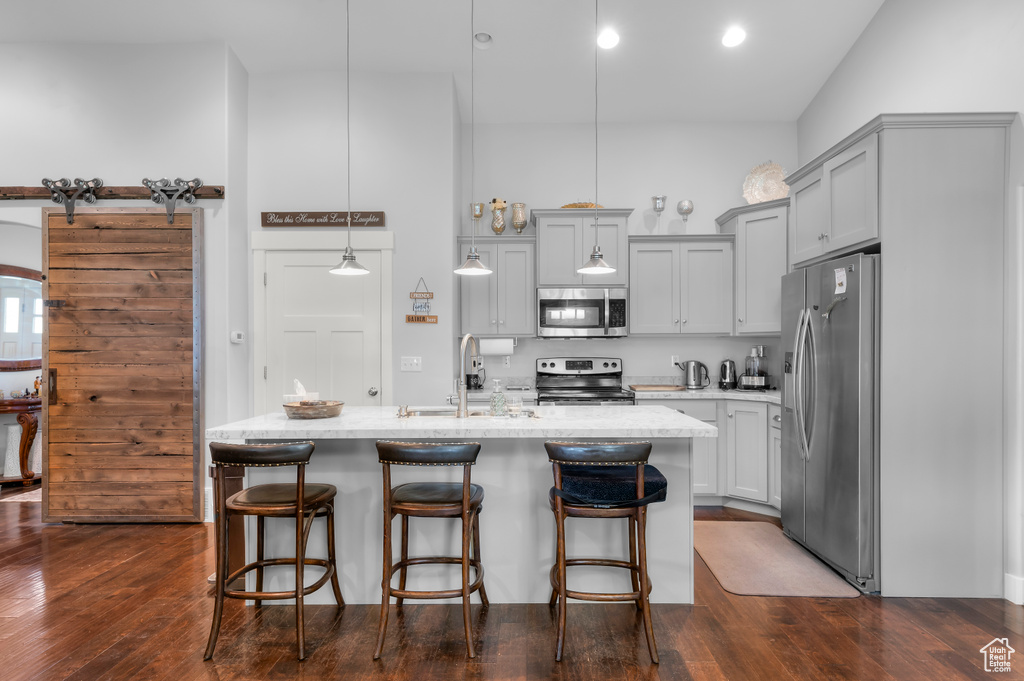 Kitchen with stainless steel appliances, a sink, gray cabinetry, and a breakfast bar area