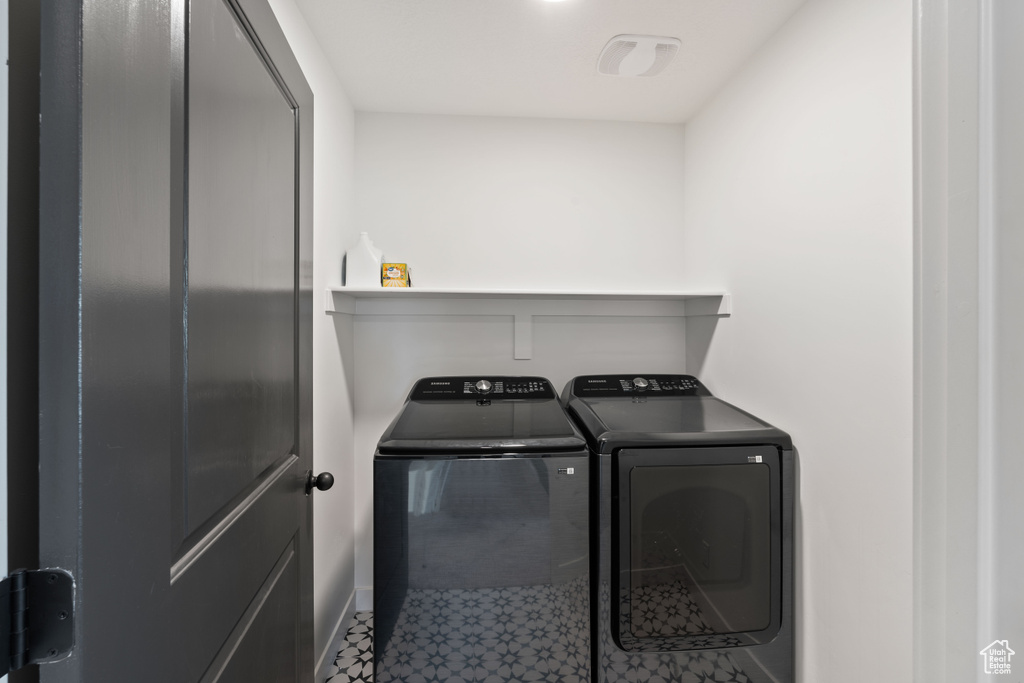Clothes washing area featuring washer and clothes dryer, baseboards, and tile patterned floors