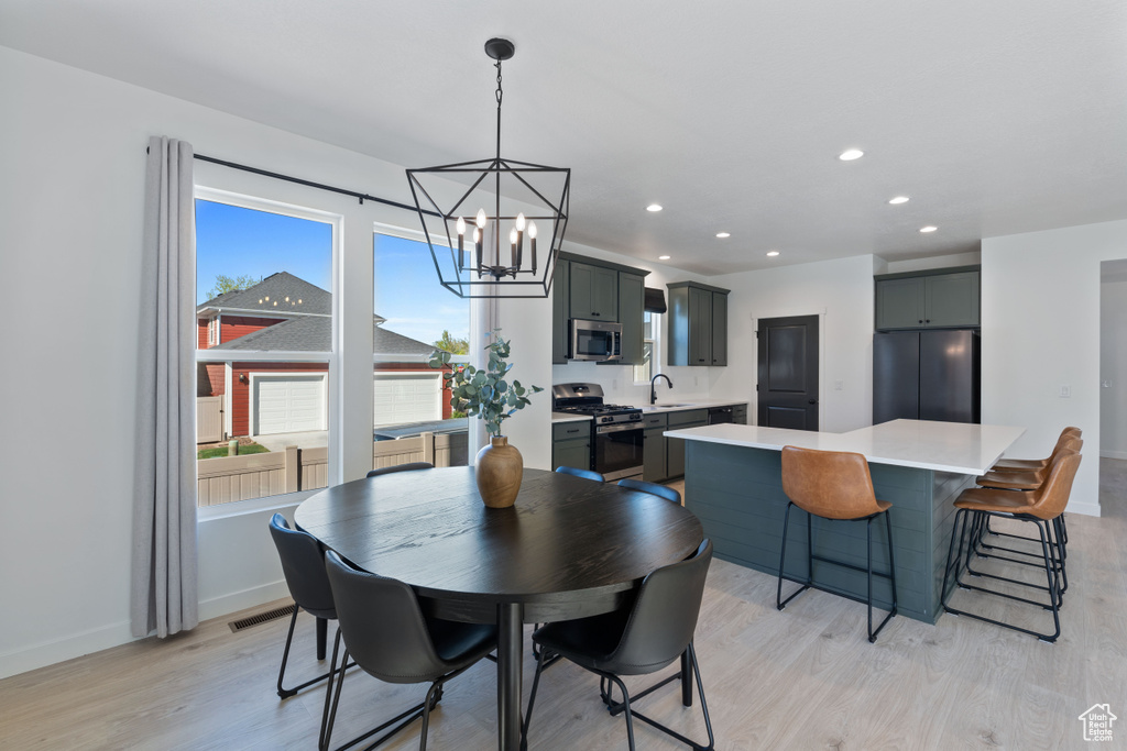 Dining area with light wood-type flooring, a chandelier, recessed lighting, and baseboards