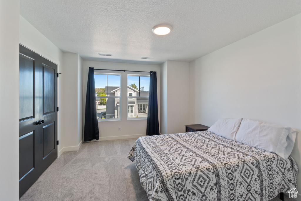 Bedroom featuring carpet floors, baseboards, and a textured ceiling