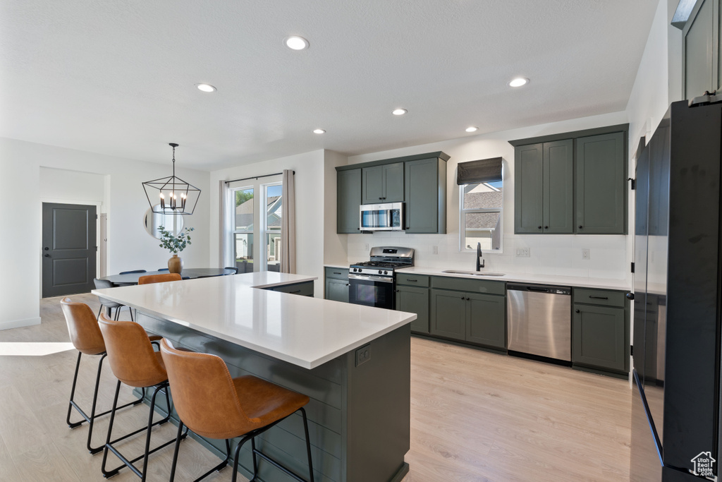Kitchen with stainless steel appliances, plenty of natural light, a sink, a kitchen island, and recessed lighting