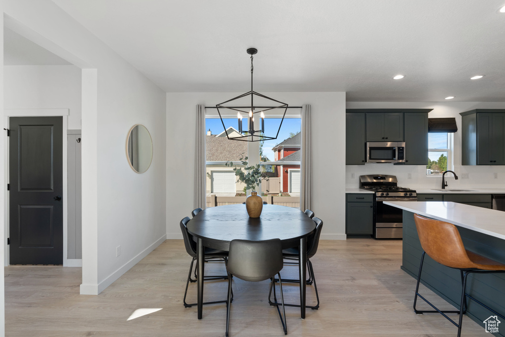 Dining area with a chandelier, light wood finished floors, baseboards, and recessed lighting