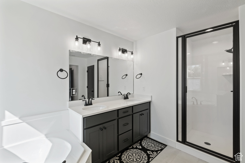 Bathroom with a stall shower, double vanity, tile patterned floors, and a bathtub