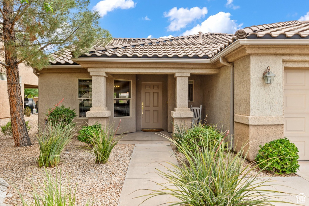 Entrance to property featuring a tile roof, stucco siding, and an attached garage