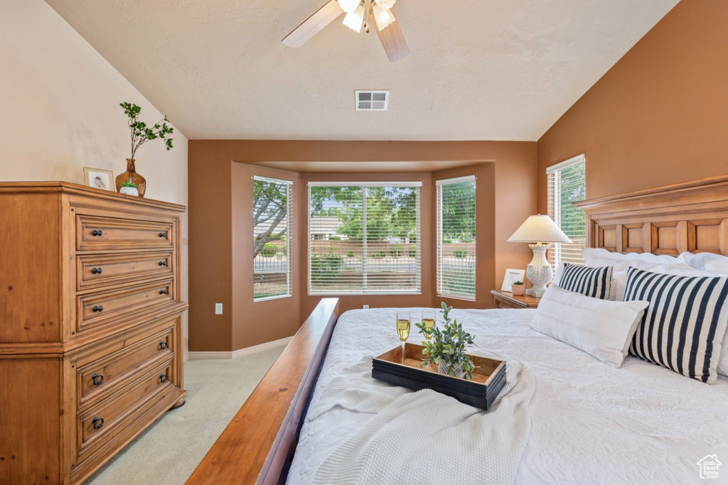 Bedroom with light colored carpet, vaulted ceiling, baseboards, and a ceiling fan