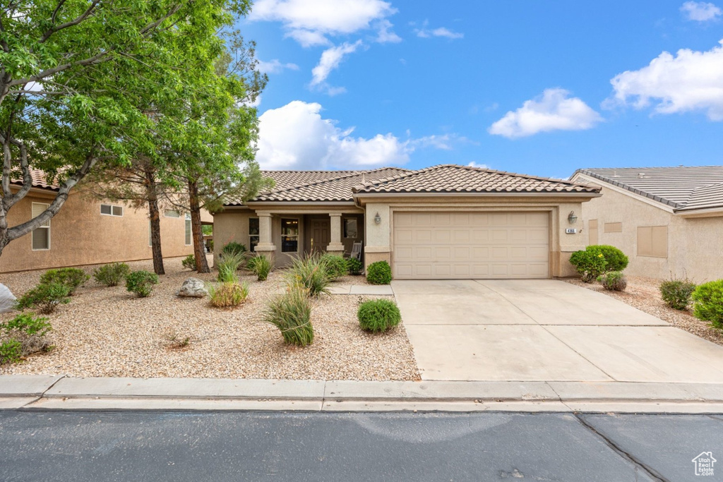 View of front facade with an attached garage, stucco siding, driveway, and a tiled roof