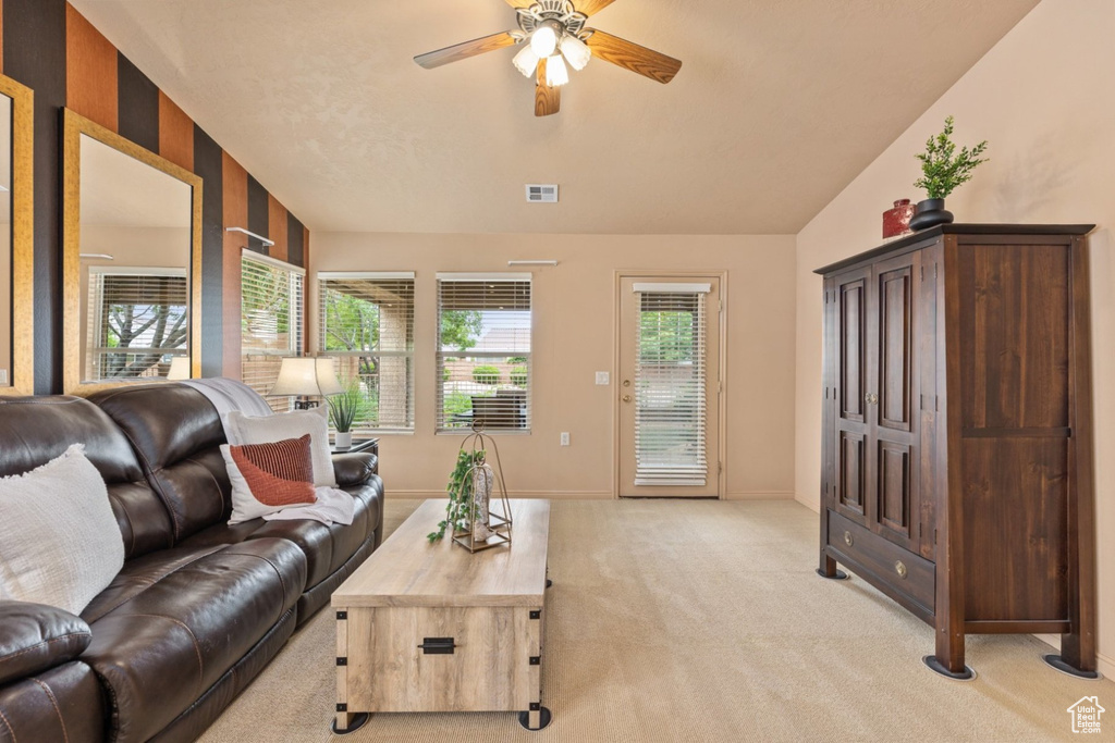 Living area with ceiling fan, light colored carpet, and baseboards