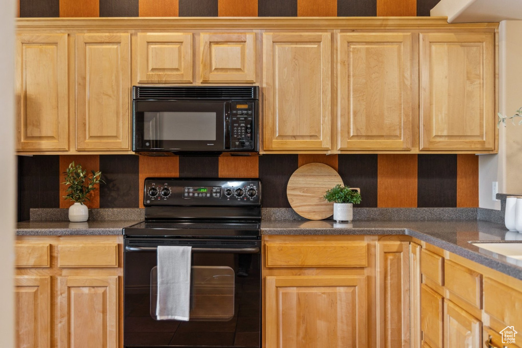 Kitchen featuring black appliances, light brown cabinetry, decorative backsplash, and dark countertops