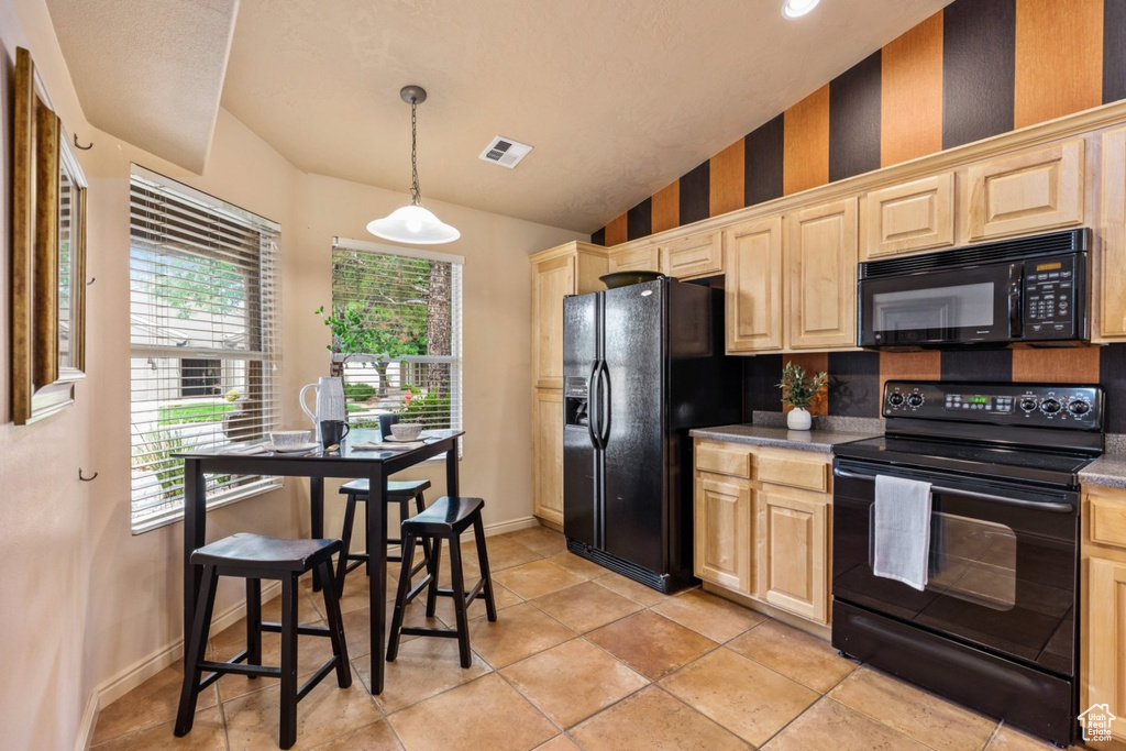 Kitchen with black appliances, light brown cabinets, healthy amount of natural light, vaulted ceiling, and baseboards
