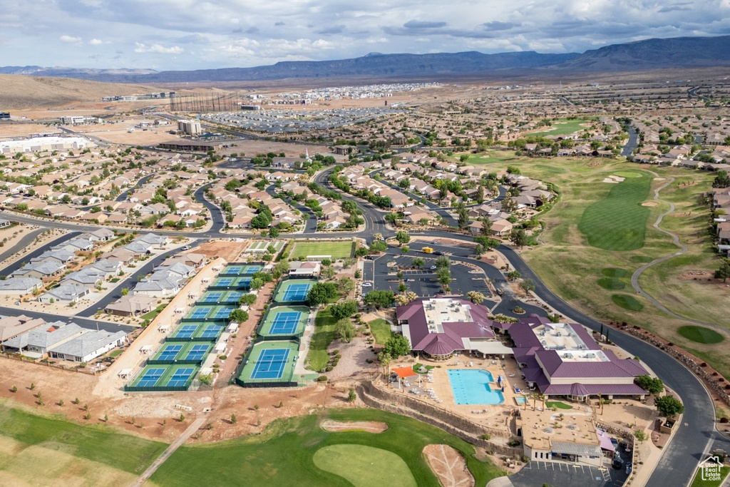 Aerial overview of property's location featuring a mountainous background, a golf course, and nearby suburban area
