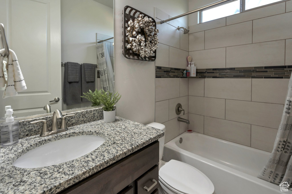 Full bathroom with shower / bath combo with shower curtain, toilet, and vanity