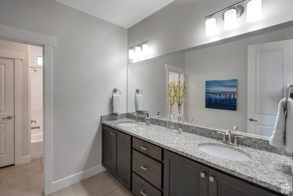 Bathroom featuring tile patterned floors, double vanity, baseboards, and bathing tub / shower combination