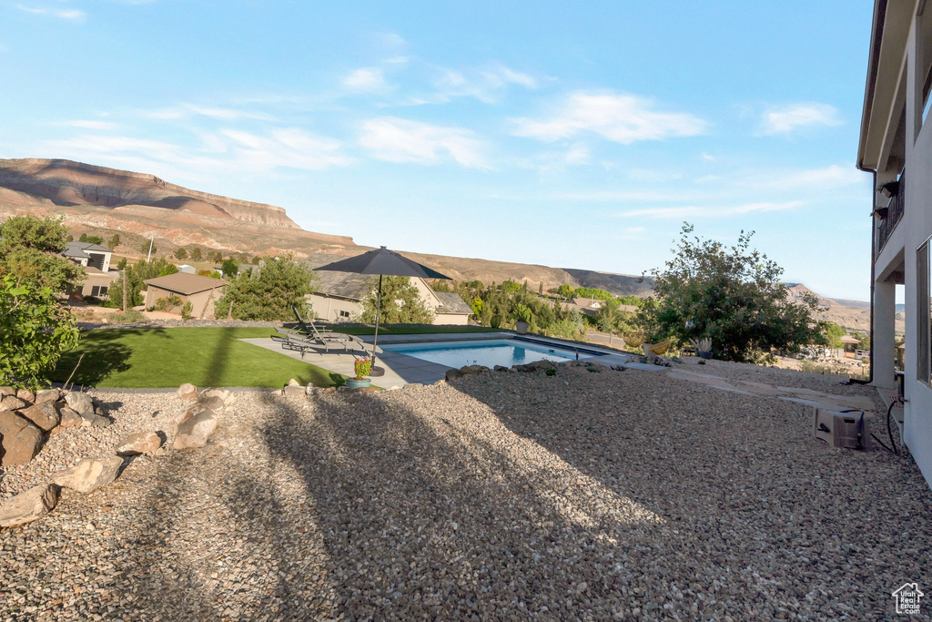 View of grassy yard featuring a patio, a mountain view, and an outdoor pool