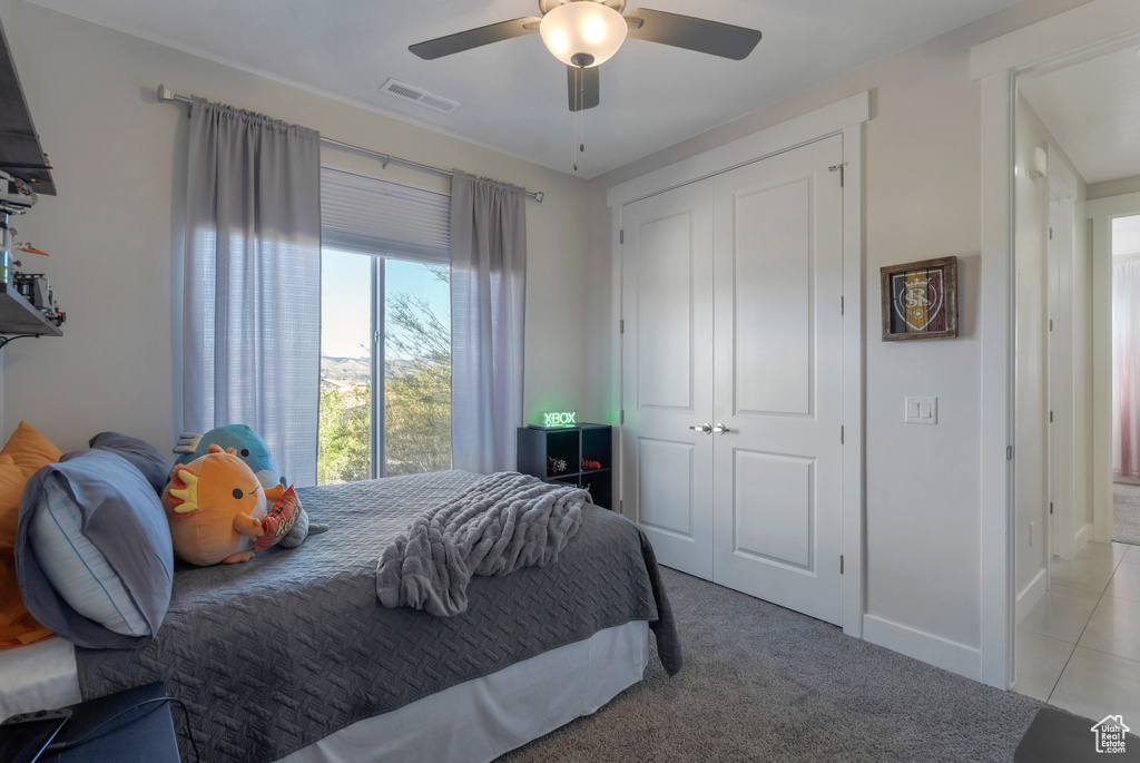 Bedroom featuring a closet, light carpet, ceiling fan, and baseboards
