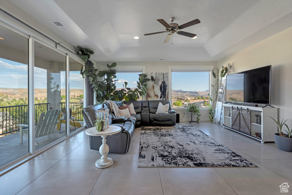 Living area with a raised ceiling, ceiling fan, and recessed lighting