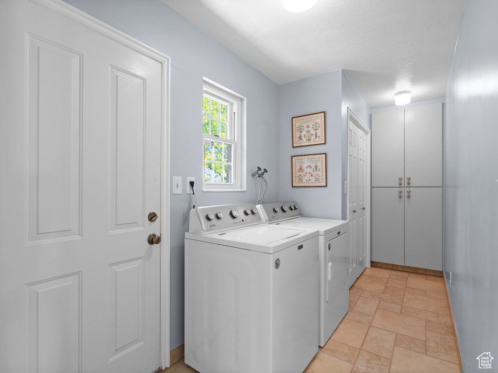 Washroom featuring separate washer and dryer and light stone finish floors