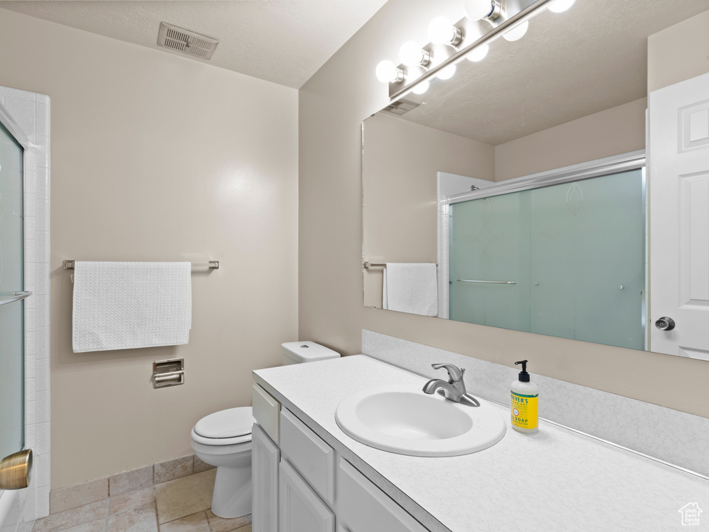Full bath featuring a shower with door, toilet, baseboards, and vanity