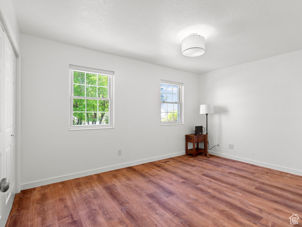 Unfurnished room with wood finished floors, healthy amount of natural light, and baseboards