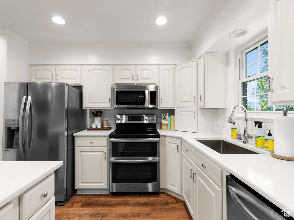Kitchen featuring stainless steel appliances, a sink, tasteful backsplash, white cabinetry, and light countertops