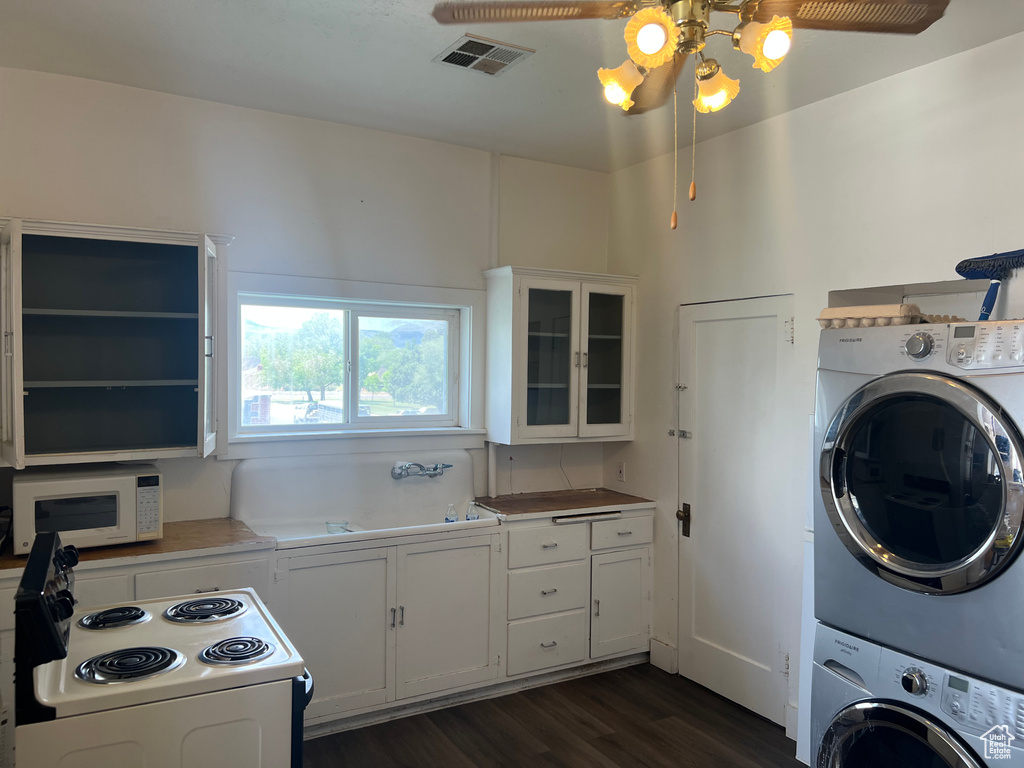 Washroom featuring stacked washing machine and dryer, dark wood-style floors, and a ceiling fan
