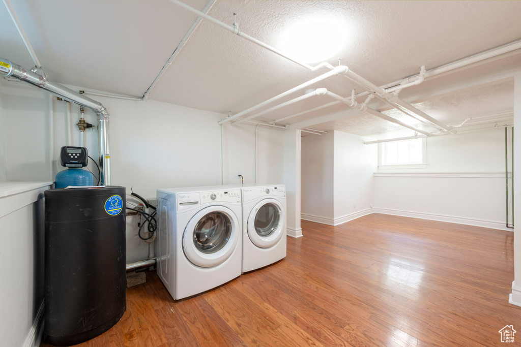 Laundry room with separate washer and dryer, light wood-style flooring, and baseboards